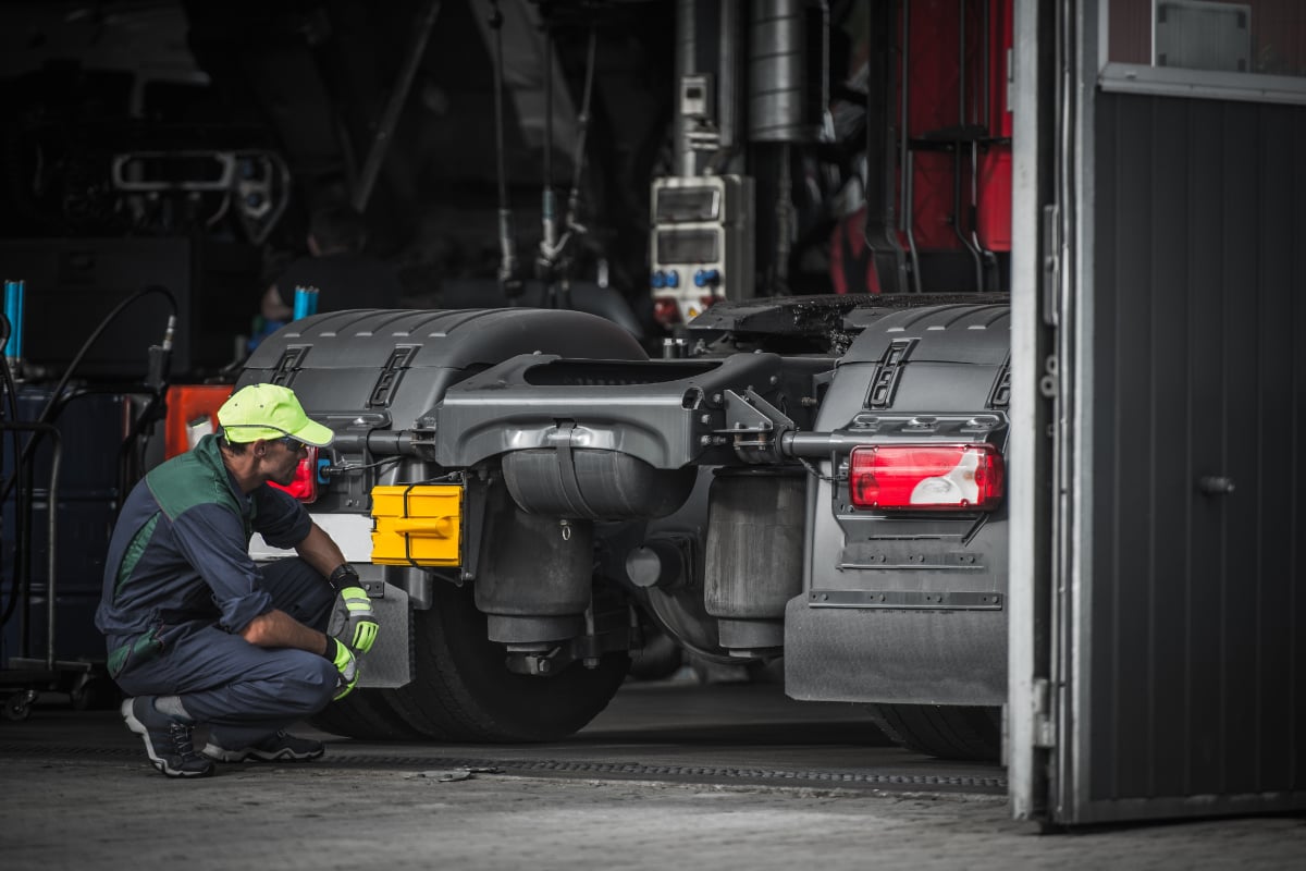 mechanic kneeling behind semi-truck